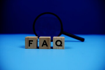 FAQ with wooden blocks alphabet letters and Magnifying glass on blue background
