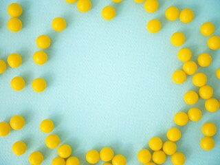 Round yellow tablets or dietary supplements are scattered on a blue background with space for text....