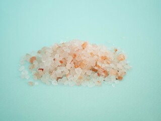 Pink Himalayan salt is scattered in large crystals on a blue background. It's lying in a pile