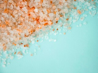 The texture of pink Himalayan salt is scattered in large crystals on a blue background. A place for the text