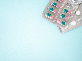 Colored tablets capsules in blisters on a blue background, a place for text. Treatment of patients