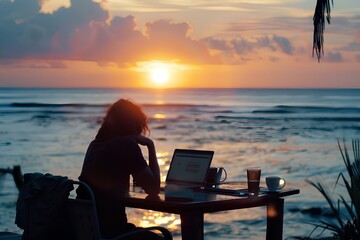 Freelancer working on laptop enjoying sunset over the ocean.