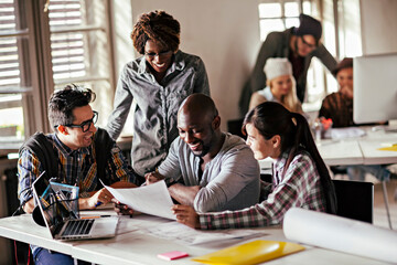 Creative team of designers collaborating on project in modern office space