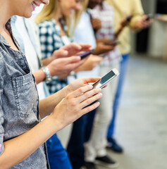 Group of diverse colleagues using smartphones together in modern office
