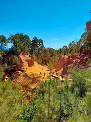 Ocher Trail in Roussillon in Provence, France. bright and lively colors along the path hidden by the trees where it seems to be in an American canyon with its orange dust. sunny day and summer