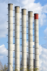 Five tall industrial pipes rising to the sky