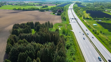 Drone view of a highway in Germany with a lot of traffic and many green fields around it.