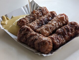 Mici cu mustar and a toothpick on a paper plate. Traditional romanian fast food. 