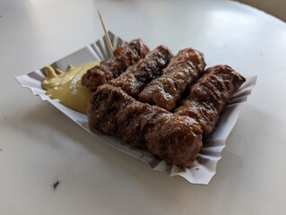 Mici cu mustar and a toothpick on a paper plate. Traditional romanian fast food. 