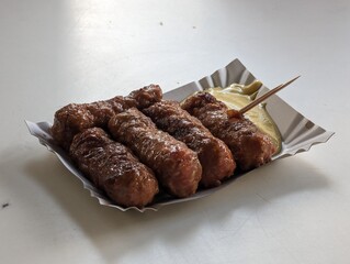 Mici cu mustar and a toothpick on a paper plate. Traditional romanian fast food. 