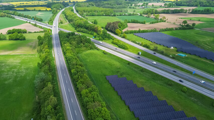 Drone view of a highway in Germany with a lot of traffic and many green fields around it.
