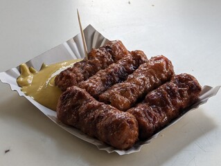 Mici cu mustar and a toothpick on a paper plate. Traditional romanian fast food. 