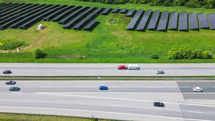 Drone flight on a German highway with lots of traffic and large solar panels next to the road.