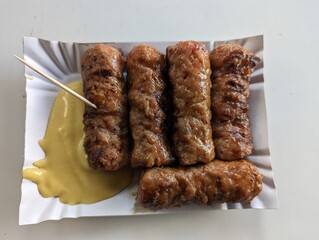 Mici cu mustar and a toothpick on a paper plate. Traditional romanian fast food. 