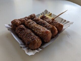 Mici cu mustar and a toothpick on a paper plate. Traditional romanian fast food. 