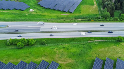 Drone flight on a German highway with lots of traffic and large solar panels next to the road.