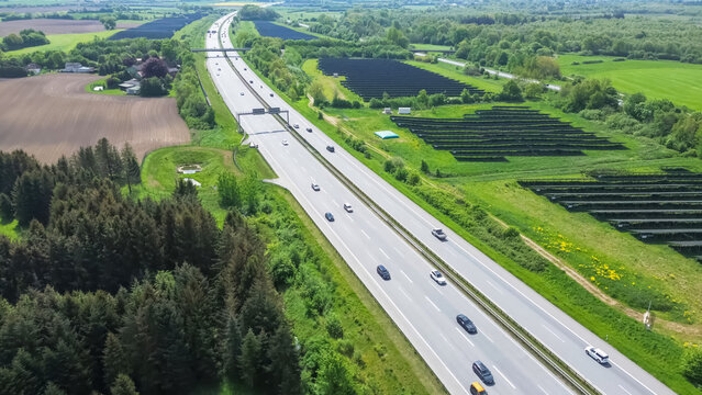 Drone flight on a German highway with lots of traffic and large solar panels next to the road.