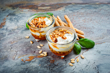 Traditional Greek honey pot served with goats cheese, pine nuts and grissini as close-up on a...