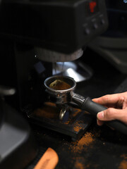 barista making ground coffee on the handle of the coffee maker to make espresso coffee