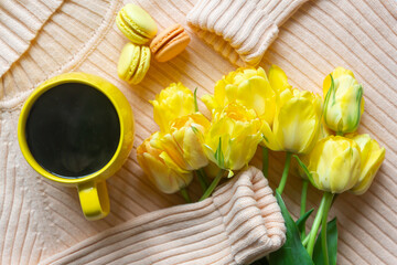 Cup of coffee, tulip flowers and French sweet macaroons.