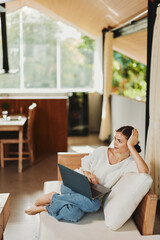 Happy Woman Working from Home on Laptop in Cozy Living Room, Enjoying Online Business Success Young...