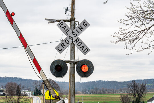 A railroad crossing sign is on a pole. The sign is red and white