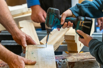 Driving screws into a board with an electric screwdriver in a carpentry workshop