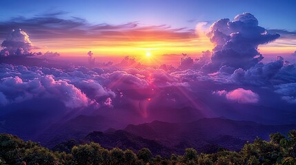   The sun descends behind a mountain range, casting clouds in the foreground and creating a backdrop of peaks in the background