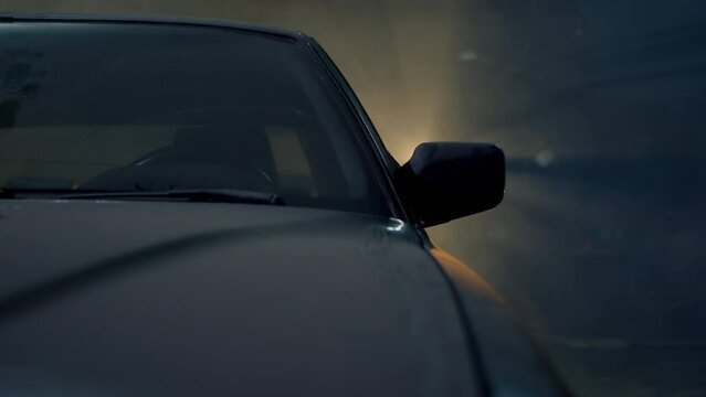 Close up view of the windshield of an old and dusty car in a garage. A car has been parked in a closed parking lot for many years. A ray of light breaks through the darkness.