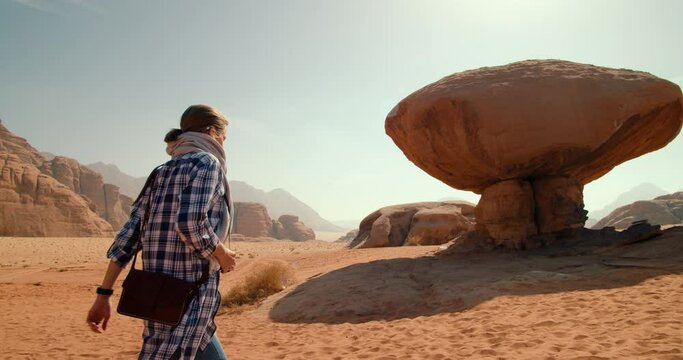 Tourist Lady photographing Mushroom Rock in Wadi Rum Desert in Jordan, Middle East. Discovery Travel and Exploring Exotic Destination by taking pictures in summer. 4K follow gimbal medium shot