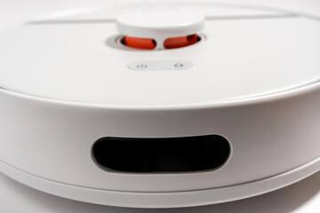 A white robot vacuum cleaner with a red button on the top.