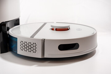 A white robot vacuum cleaner with a blue container on the bottom.