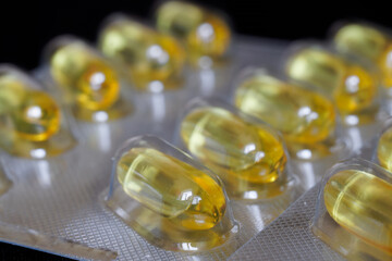 Fragments of blisters with golden capsules with fish oil. The concept of using vitamin D for the...