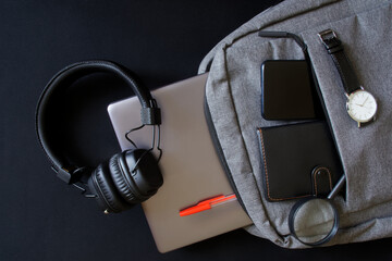 Gray textile backpack with laptop or ultrabook, magnifying glass, wallet and wristwatch lies next...