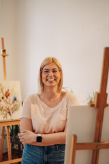 A creative smiling artist posing in art studio with arms crossed.