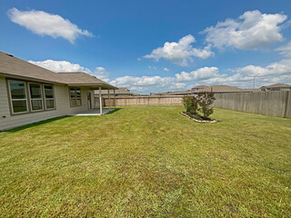 Suburban House Large Backyard with Wood Fence on a Cloudy Sky, Grass Maintained.