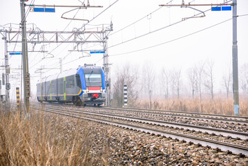 Diesel passenger train running through the countryside on a foggy winter day