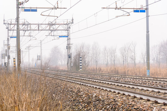 Deserted stretch of a double-track railway through the countryside on a foggy winter day