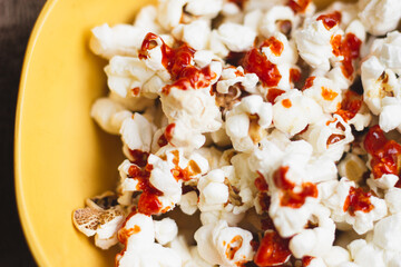 Popcorn with hot sauce in a yellow bowl on a vintage table