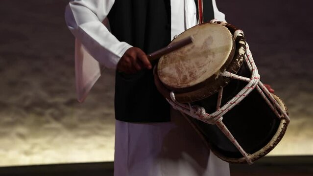 Man playing traditional Emirati drums percussion instrument, hands only in frame