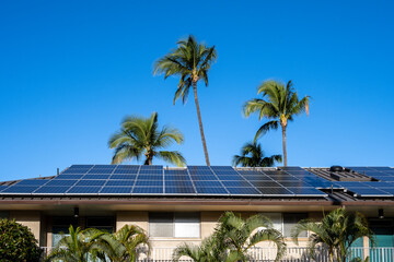 Condo building roof covered in solar panels to generate green alternative energy on sunny Maui, in...