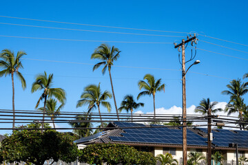 Condo building roof covered in solar panels to generate green alternative energy on sunny Maui, in...