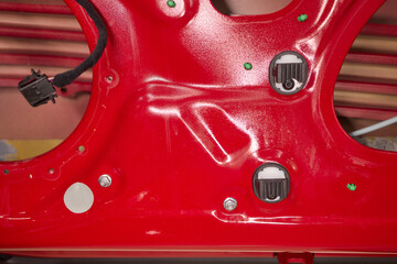 Closeup of red car door with perforated holes in automotive exterior