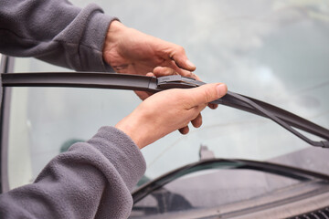 Hand changing car windshield wiper, using thumb and fingers