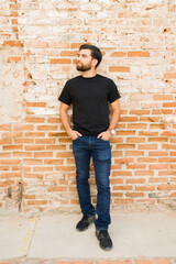 Confident young hispanic man wearing a blank black t-shirt for mockup presentation, standing...