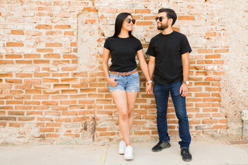 Trendy hispanic couple in plain t-shirts and casual attire, ideal for mock-up designs, confidently...