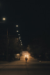 Silueta de persona iluminada por un automóvil en la ciudad de noche