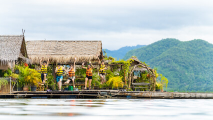 Group of Young Asian man and woman friends with life vest jumping into the lake and swimming...