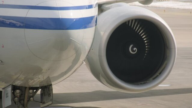 Aircraft engine turbine spins under wing of airplane close-up.