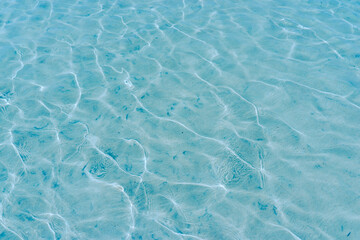 Sun lights shadow in wavy water on abstract sand background